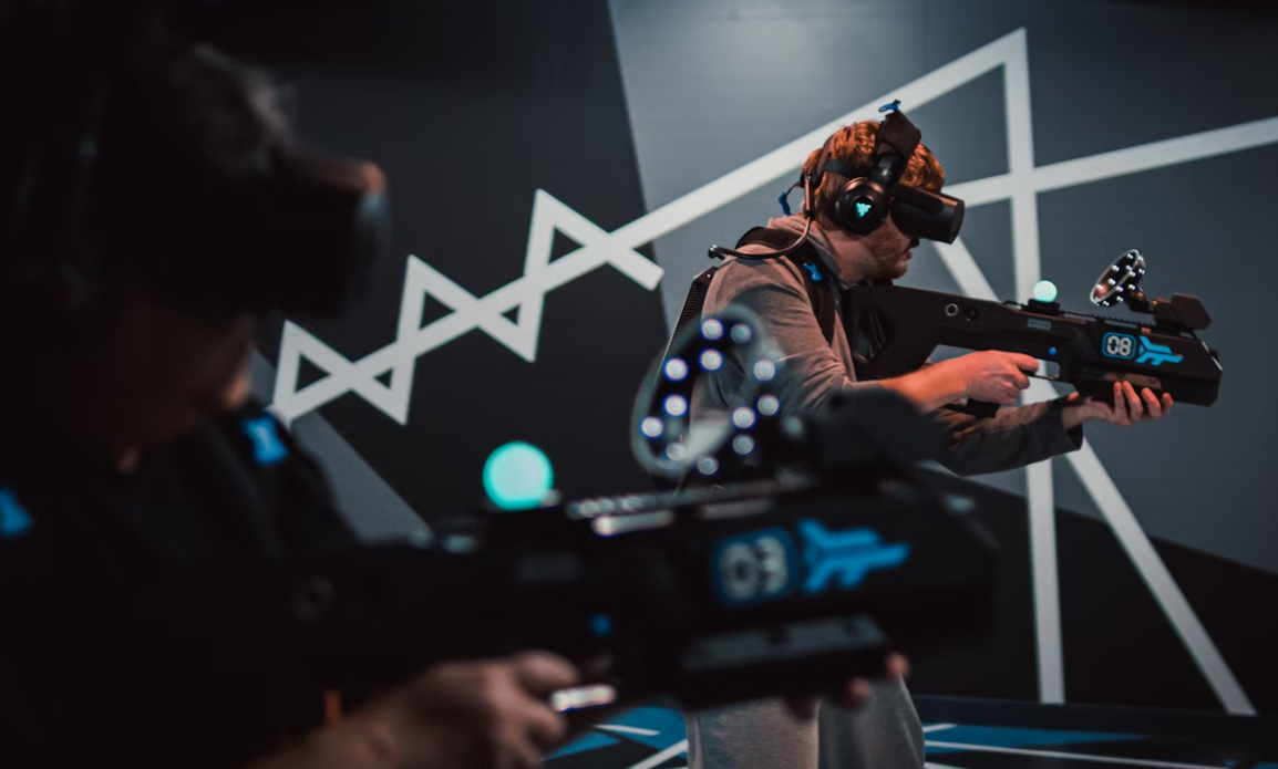 deux jeunes hommes portant un casque de réalité virtuelle avec de faux pistolets aux mains