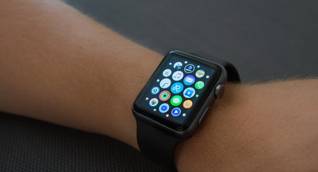 montre connectée noire  avec des logos  accrochée à un poignet