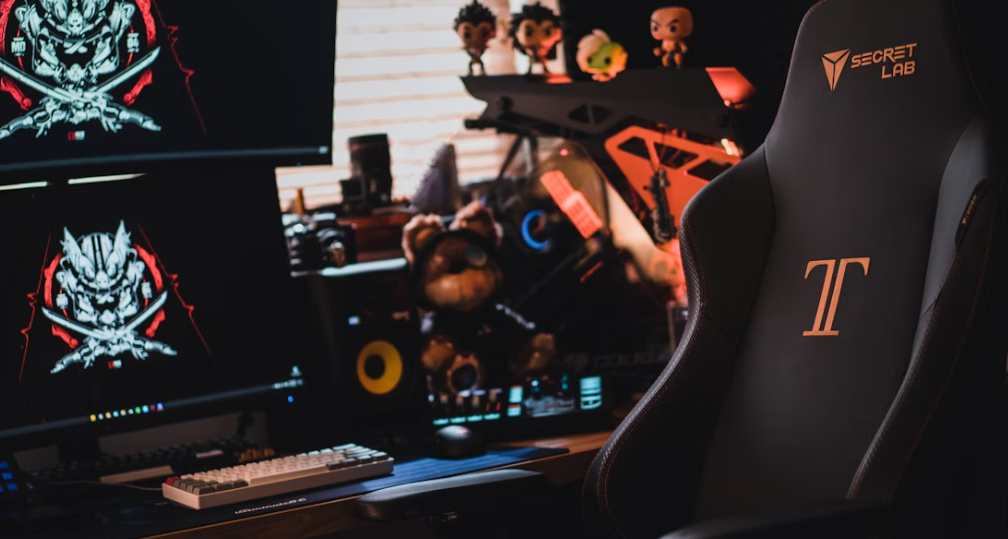 zoom sur un bureau avec 2 écrans pc et des figurines à droite et une chaise gaming noire devant