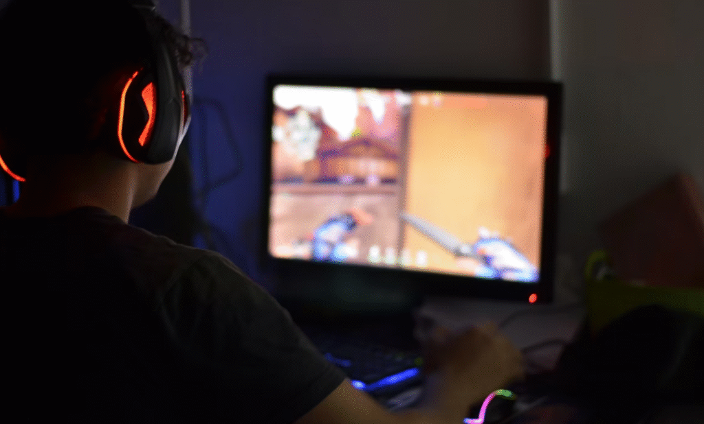 jeune homme de dos jouant aux jeux video sur son pc