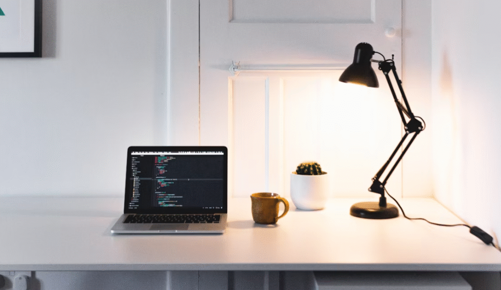 pc portable sur un bureau avec une lampe de bureau à droit et une tasse au centre