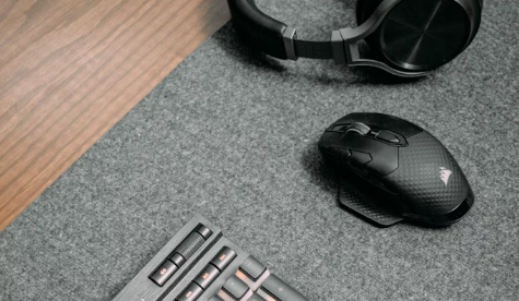 souris noire posée sur un tapis de souris gris à côté d'un casque noir