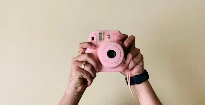 vue sur les deux mains d'une femme en train de prendre une photo avec un appareil instax